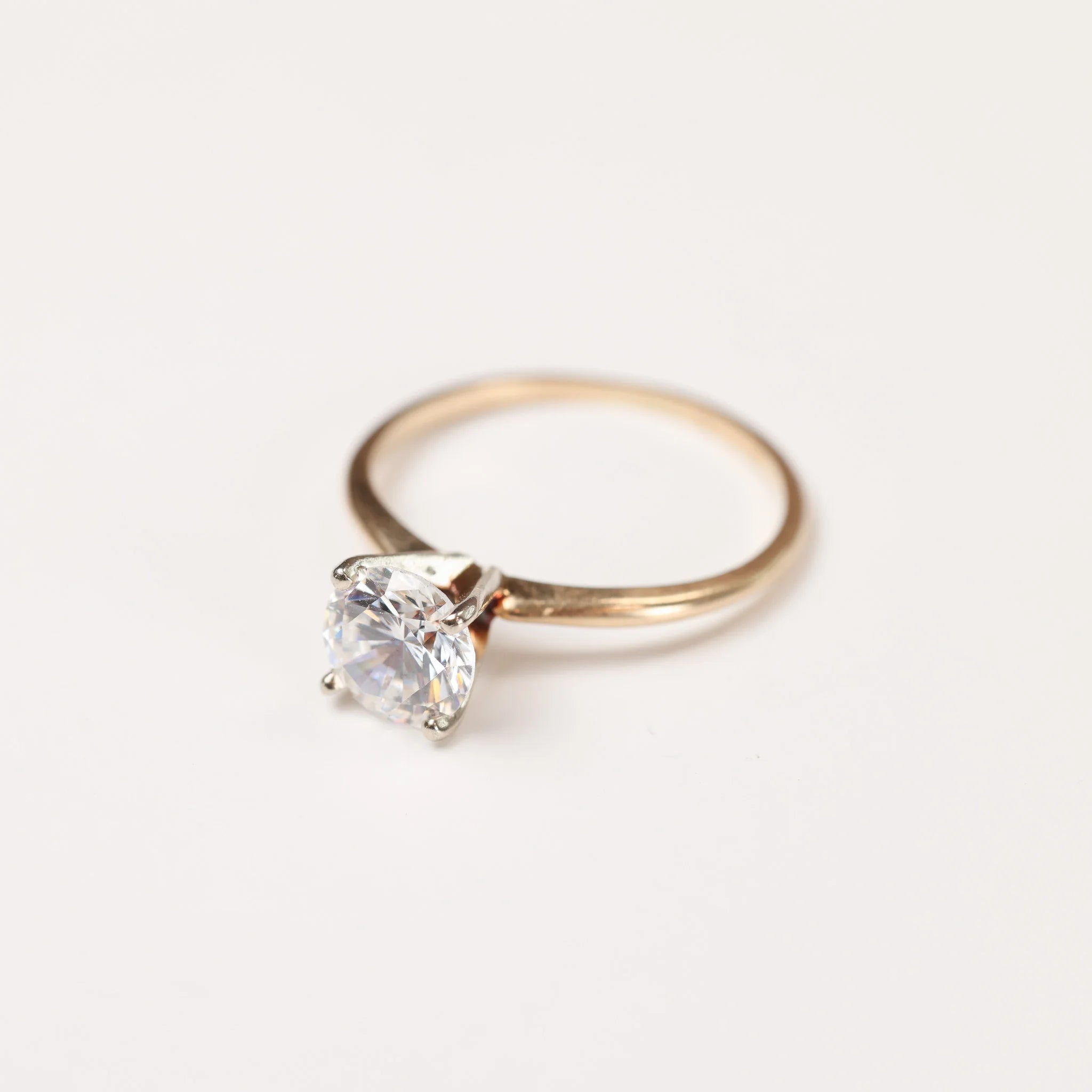 A gold diamond ring lays on a white background.