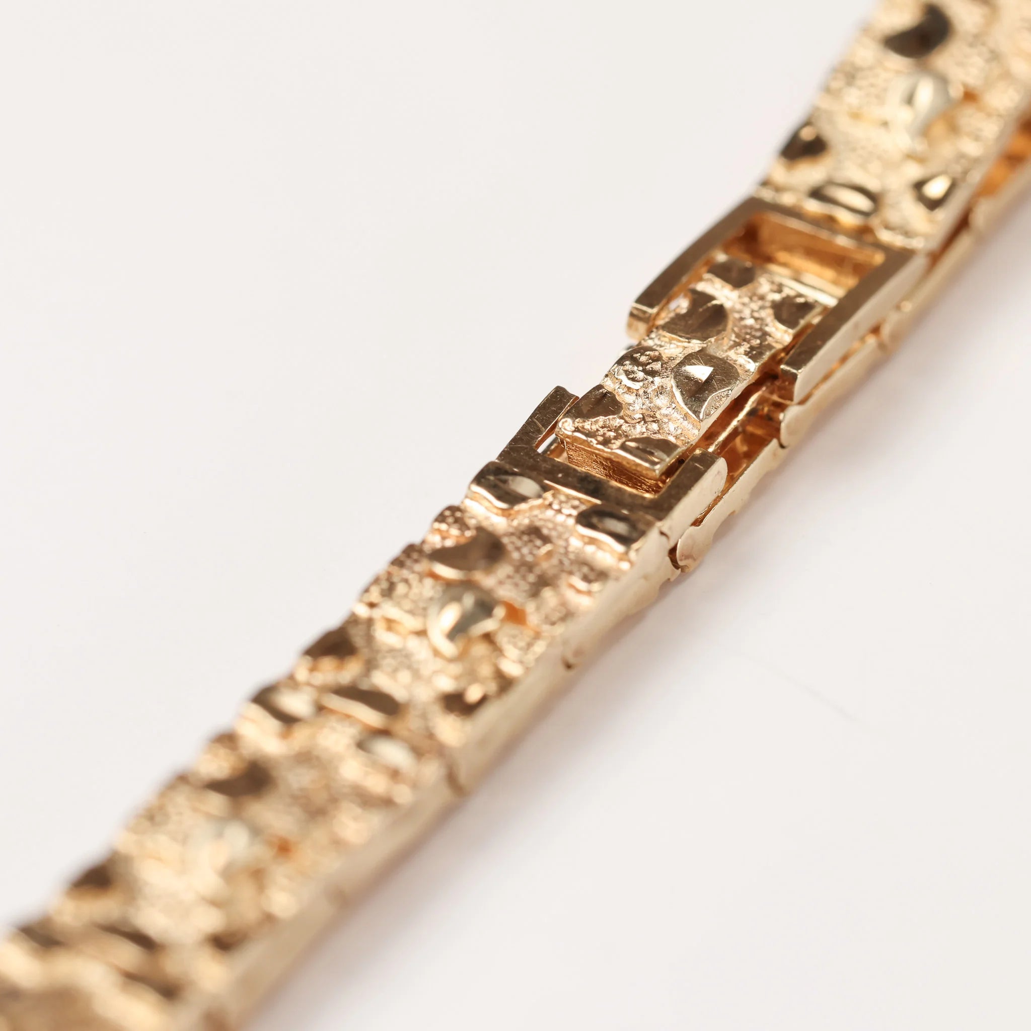 A gold men's nugget bracelet on a white background