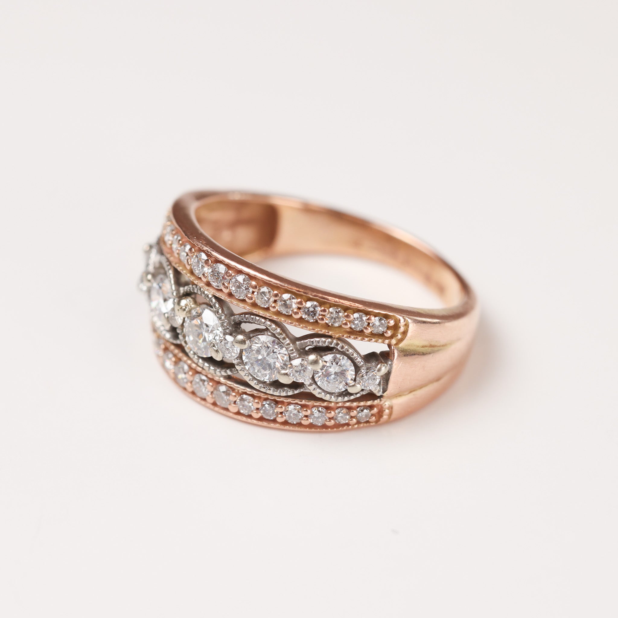 A yellow gold diamond ring sits on a white background.