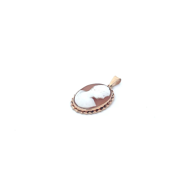 A white and brown cameo pendant on a white background.