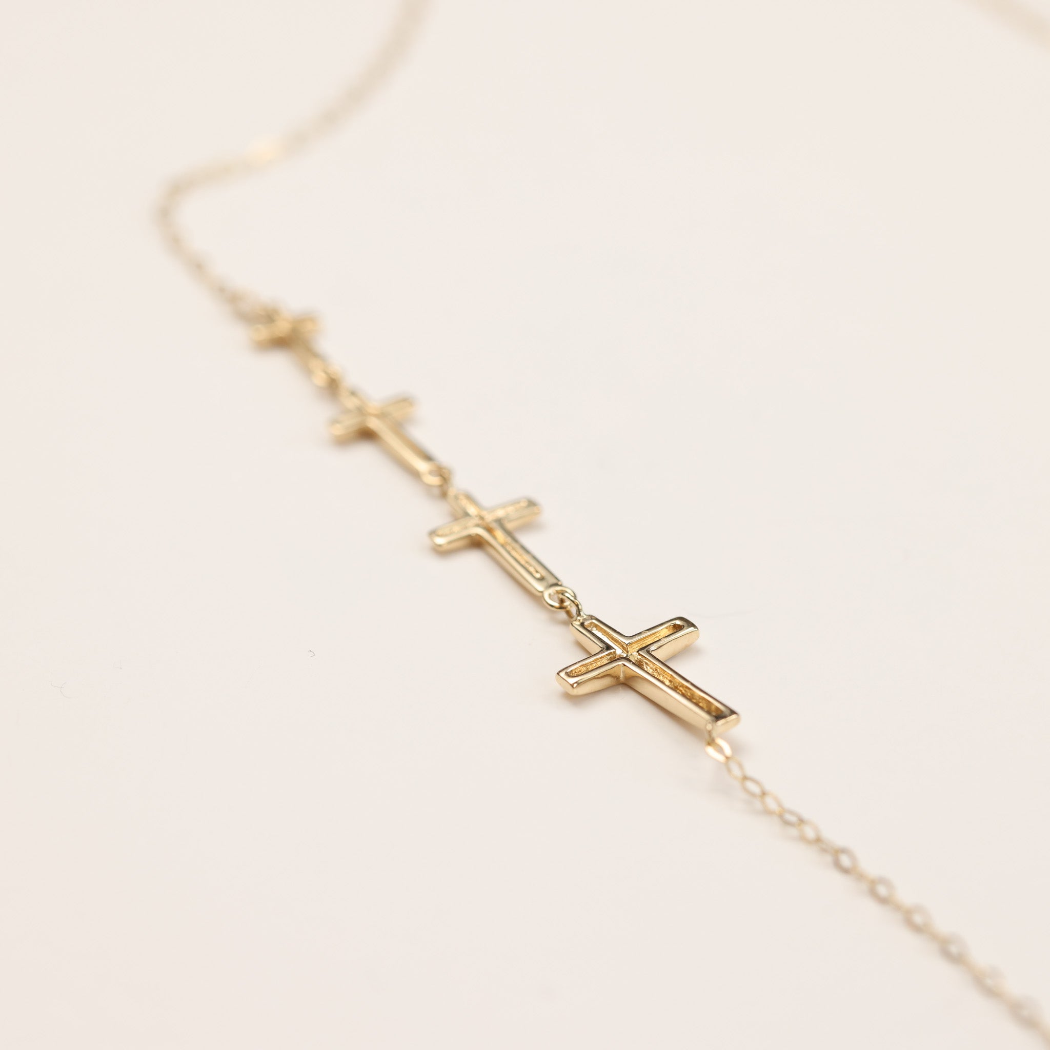 A delicate 14 Karat Yellow Gold Tanzanite Diamond Ring - Size 5 featuring small cross pendants aligned in a row on a thin chain.