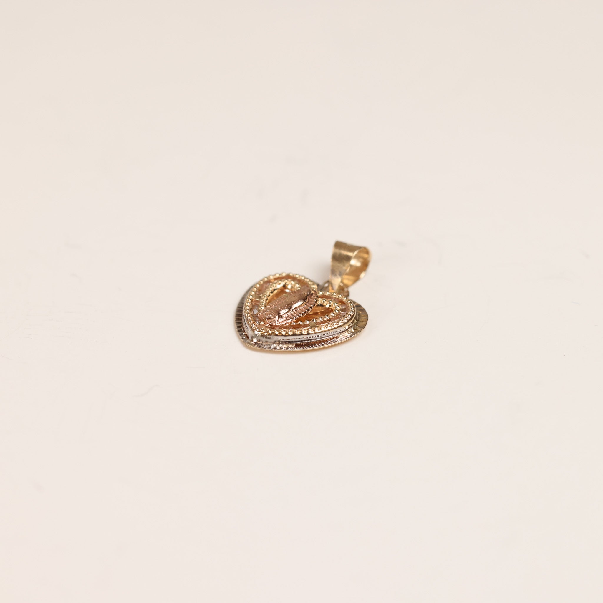 A gold heart-shaped pendant with intricate detailing and a small gemstone at the center, displayed on a white background, reminiscent of a 14 Karat Yellow Gold Tanzanite Diamond Ring - Size 5.