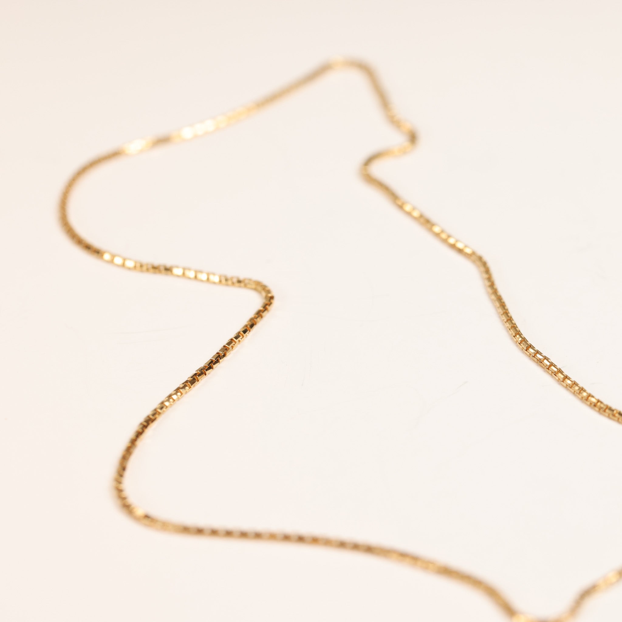 A close-up image of a thin gold chain necklace lying on a light surface, showcasing its delicate 14 Karat Yellow Gold Tanzanite Diamond Ring - Size 5.