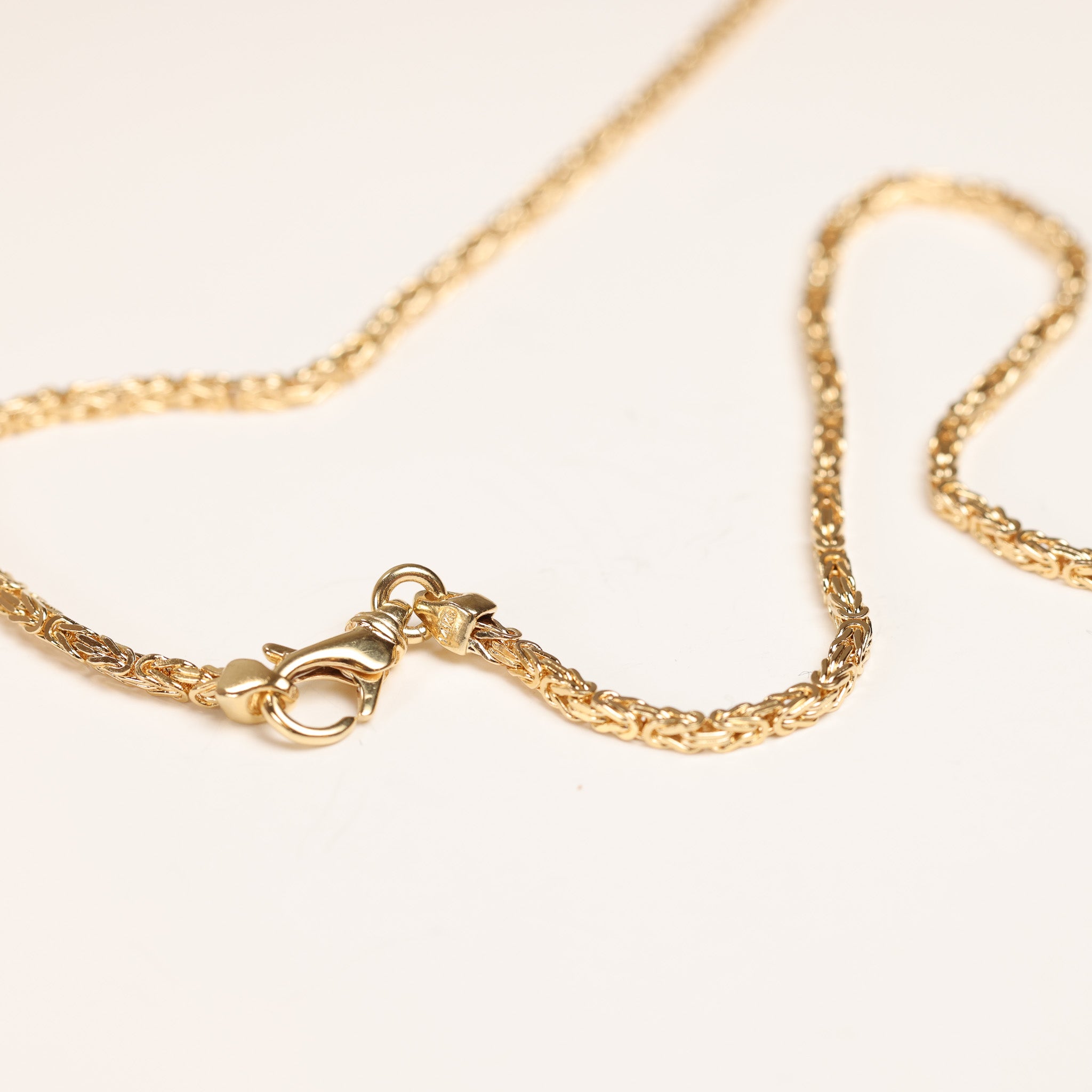 Gold necklace with a lobster clasp, laid out on a light background, complements the stunning 14 Karat Yellow Gold Tanzanite Diamond Ring - Size 5.