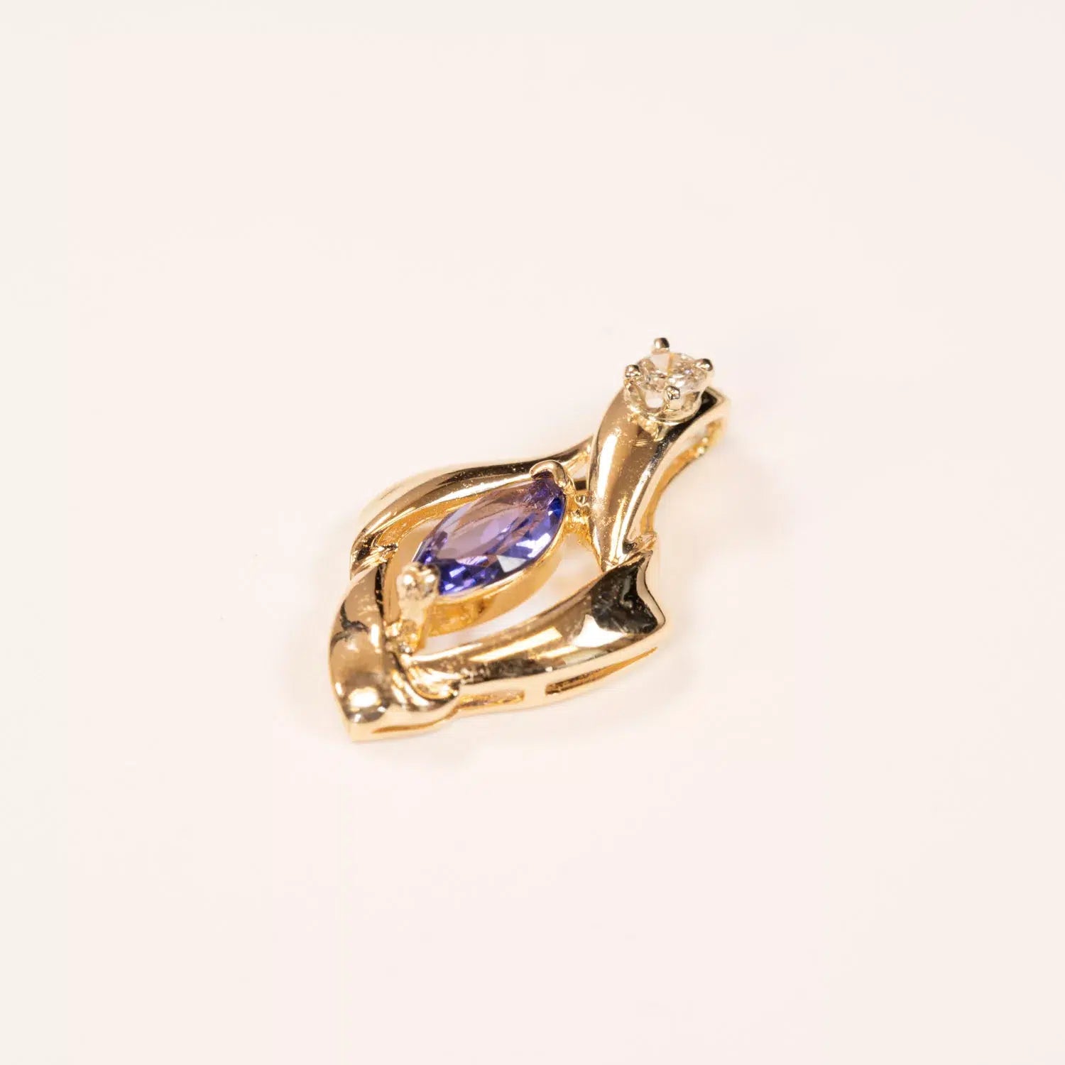 14K YG Tanzanite & Diamond Pendant in the shape of a swan, featuring a tanzanite gemstone and a small clear crystal, against a white background.