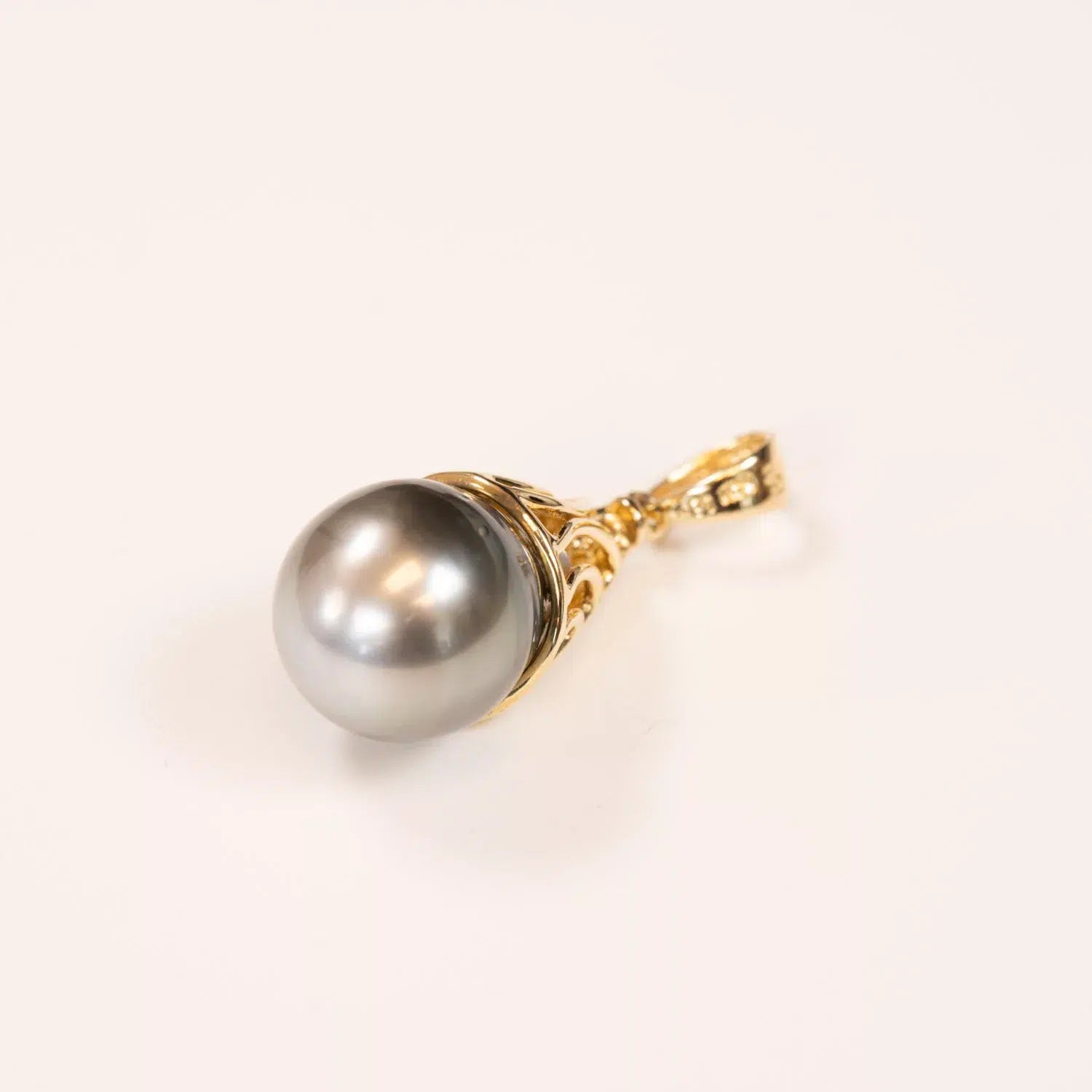 A single pearl earring with a gold setting and a 14K YG Tanzanite & Diamond pendant on a white background.