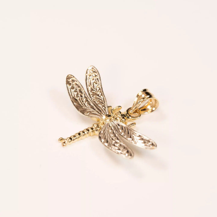 A golden 14K YG Tanzanite & Diamond pendant with detailed wing textures, positioned against a plain white background.