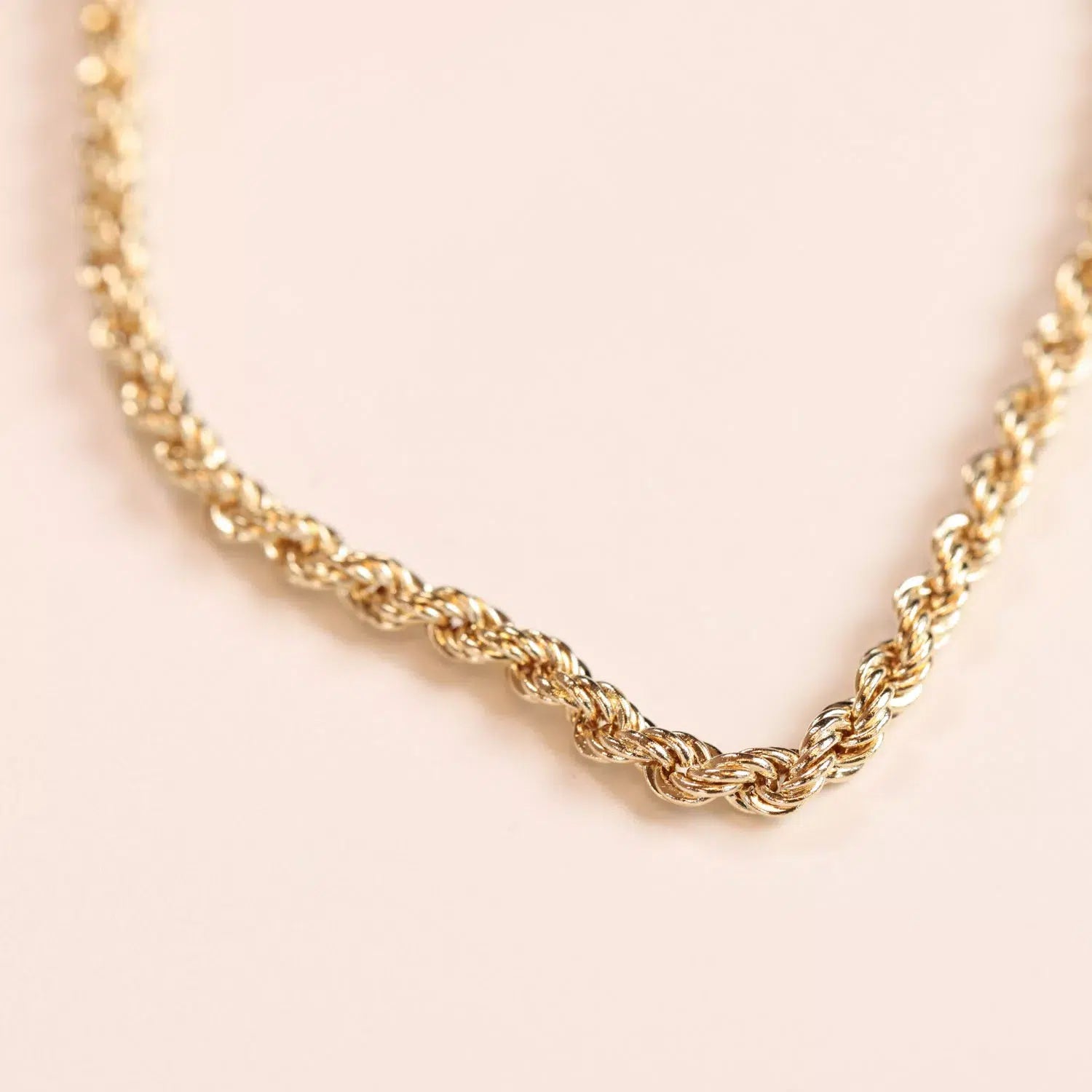 14 Karat Yellow Gold Figaro 25" Chain necklace on a light pink background.