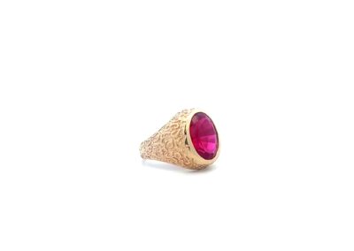 A gold ring with a pink stone.