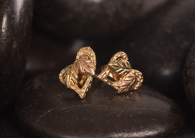 A pair of 14 Karat Yellow Gold White Stone Tennis Bracelet stud earrings on a black stone.