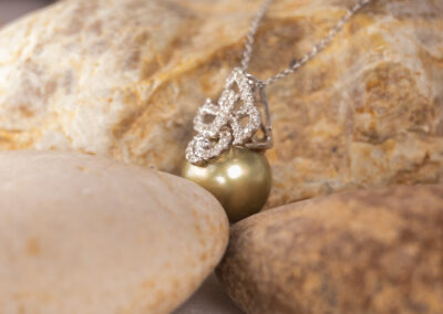 A 14 Karat White Gold Pearl Diamond Necklace with a pearl and diamonds on top of a rock.
