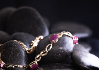 A 14 Karat yellow gold Ruby bracelet with ruby stones on a black background.
