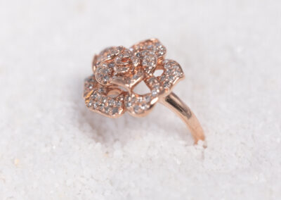 A rose gold ring with diamonds on top of snow.