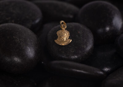 A 14 Karat Yellow Gold charm on a white stone.