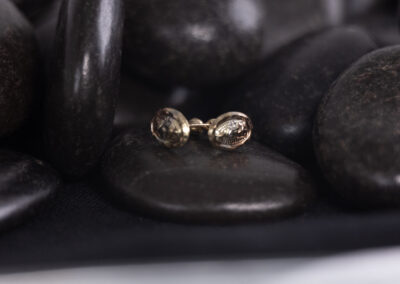 A pair of 14 Karat yellow gold stud earrings on a bed of white stones.