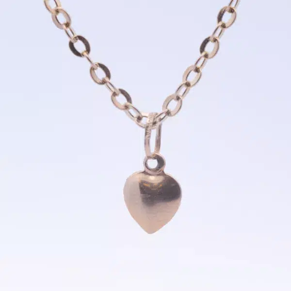A small gold heart charm on a 14 Karat Yellow Gold chain.