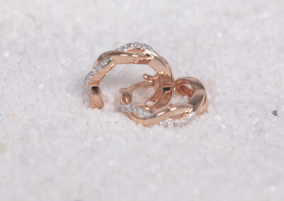 A pair of rose gold hoop earrings with a 14 Karat Yellow Gold White Stone Tennis Bracelet shine, laying in the soft sand.