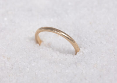 A 14 Karat Yellow Gold Band sparkles on top of a pile of snow, contrasting the icy landscape with its brilliant 14 Karat Yellow Gold.