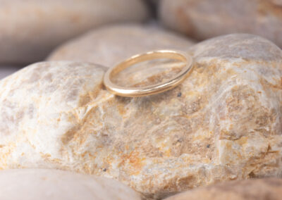 A 14 Karat Yellow Gold Band sits on top of rocks.