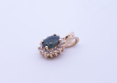 A pendant with a green stone and diamonds, set in 14 Karat Yellow Gold White Stone Tennis Bracelet.