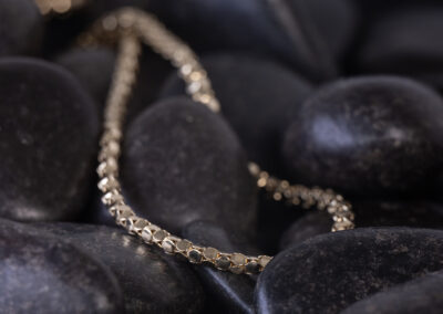 A 14 Karat Yellow Gold White Stone Tennis Bracelet, laid on a black background.