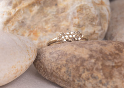 A 14 Karat Yellow Gold White Stone Tennis Bracelet sits on top of some rocks.