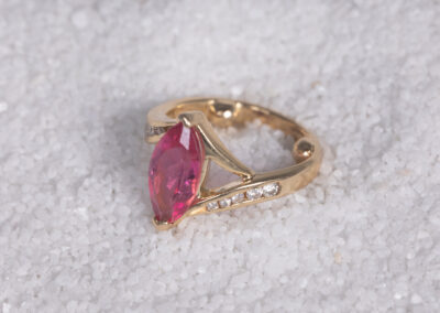 A 14 Karat Yellow Gold White Stone Tennis Bracelet with a pink stone and diamonds.