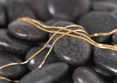 A stack of black stones with a 14 Karat Yellow Gold Fashion Chain.