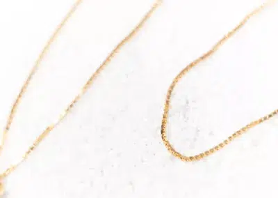 Two 14 Karat Yellow Gold Fashion Chains on a white surface.