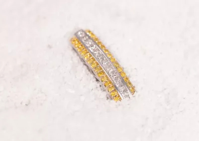 A yellow and white diamond ring, made of 14 Karat Yellow Gold Fashion Chain, laying in the snow.