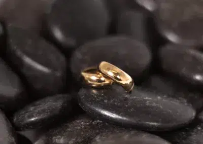 A pair of 14 Karat Yellow Gold Fashion Chain rings on a pile of black rocks.
