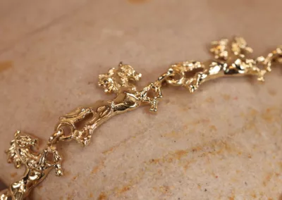 14 Karat Yellow Gold Figaro 25" Chain with floral design resting on a stone surface.