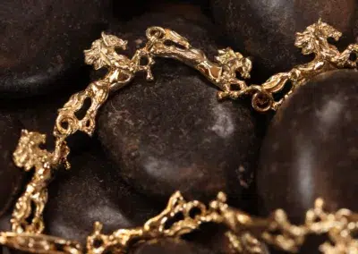 Ornate 14 Karat Yellow Gold Figaro 25" Chain on smooth dark stones.