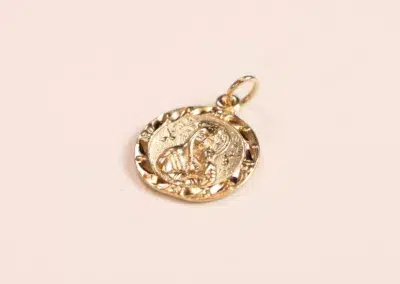 14 Karat Yellow Gold Figaro 25" Chain pendant with embossed design on aplain background.