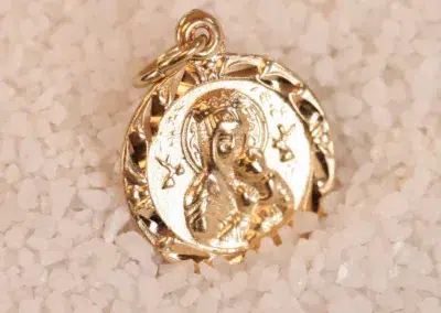 14 Karat Yellow Gold Figaro 25" Chain pendant with religious iconography nestled in white grains, possibly sand or small crystals, suspended from.