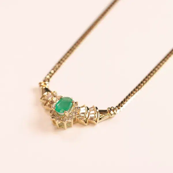 14 Karat Yellow Gold Figaro 25" Chain necklace with a central emerald and surrounding diamonds, set against a white background.
