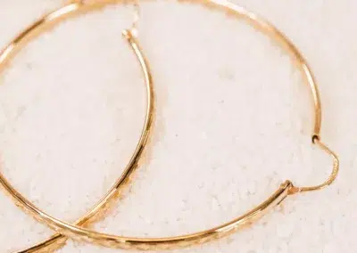 A pair of 14 Karat Yellow Gold Comfort Fit Band hoop earrings on a white surface.