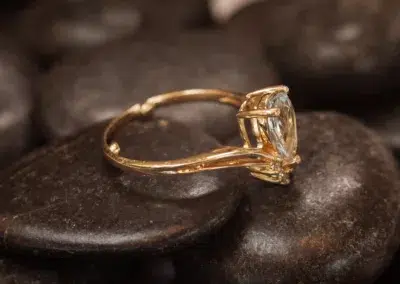 A 14 Karat Yellow Gold Comfort Fit Band ring with a blue topaz stone on top of rocks.
