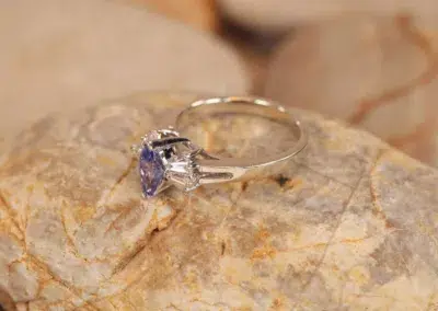 A tanzanite and diamond ring on a rock, featuring a 14 Karat Yellow Gold Comfort Fit Band.