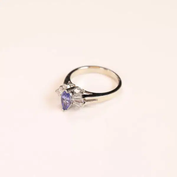 A tanzanite and diamond ring on a white surface, featuring the 14 Karat Yellow Gold Comfort Fit Band.