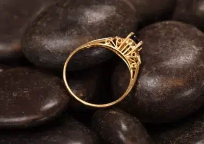 14 Karat Yellow Gold Comfort Fit Band sitting on a pile of rocks.
