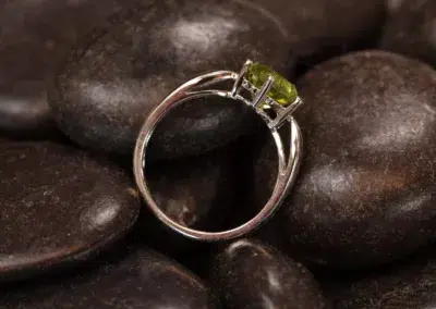A ring with a peridot on top of rocks, featuring the 14 Karat Yellow Gold Comfort Fit Band.