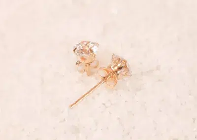 Rose gold stud earrings with cubic zirconia and a 14 Karat Yellow Gold Comfort Fit Band.
