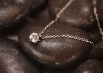 A silver necklace with a 14 Karat Yellow Gold Comfort Fit Band diamond on it.