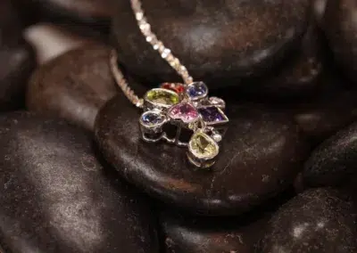 A necklace with multi-colored stones on top of rocks features a Diamond 14 Karat Yellow Gold Comfort Fit Band.