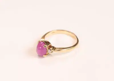 A 14 Karat Yellow Gold Comfort Fit Band with a pink stone.