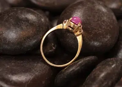 A 14 Karat Yellow Gold Comfort Fit Band with a ruby stone on top of rocks.