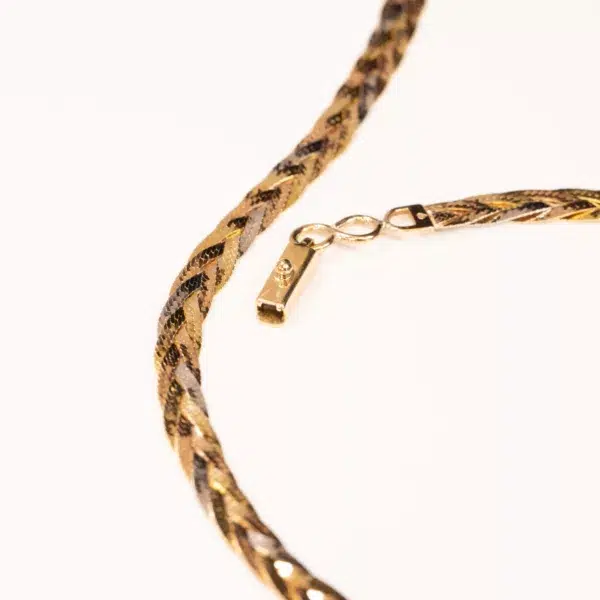 A close-up of a snake chain necklace with a clasp, featuring a patterned design in gold and black, embellished with a 14K YG Tanzanite & Diamond Pendant, against a white