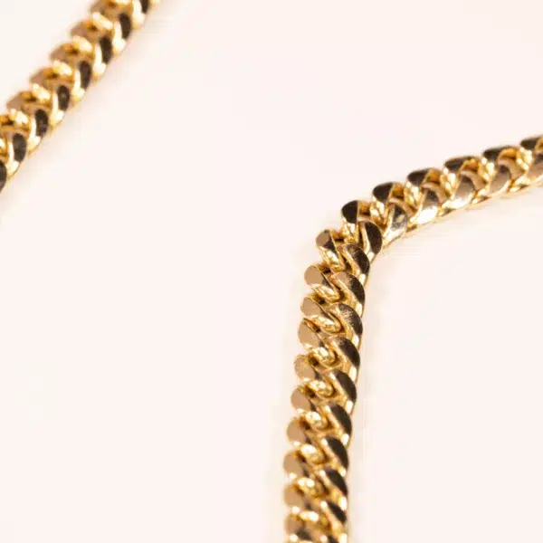 Close-up view of two intersecting 10 Karat Yellow Gold Ram Rings on a white background, focusing on the intricate links of the chains.