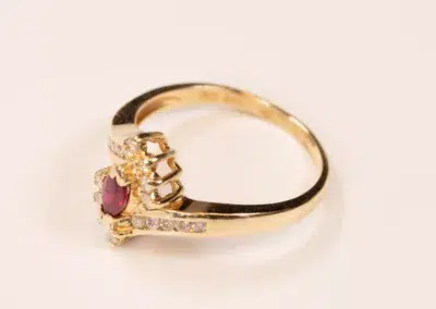 10 Karat Yellow Gold Ram Ring featuring a pink gemstone surrounded by small diamonds on a plain white background.